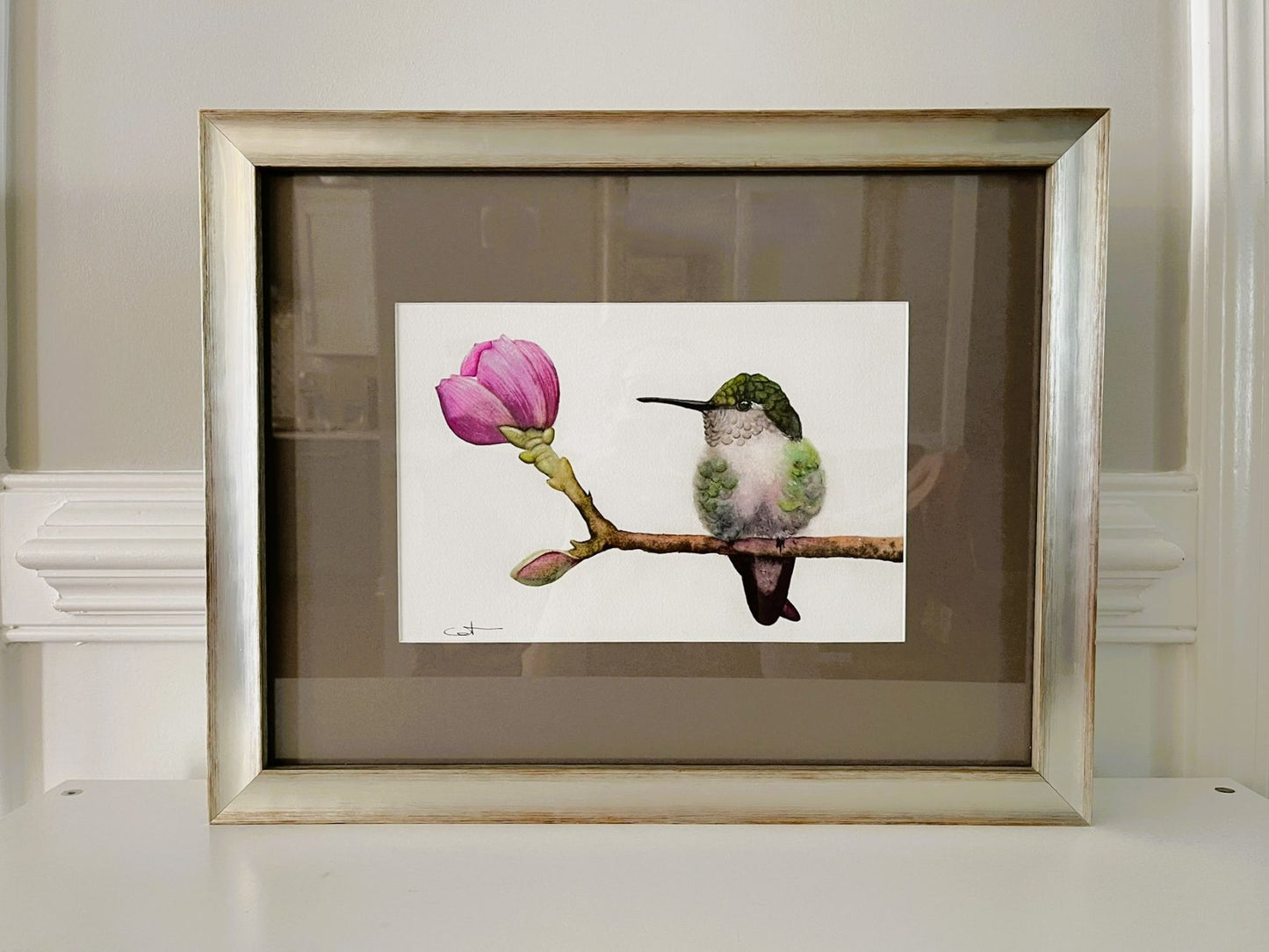 Framed watercolor  artwork of a hummingbird and pink flower.