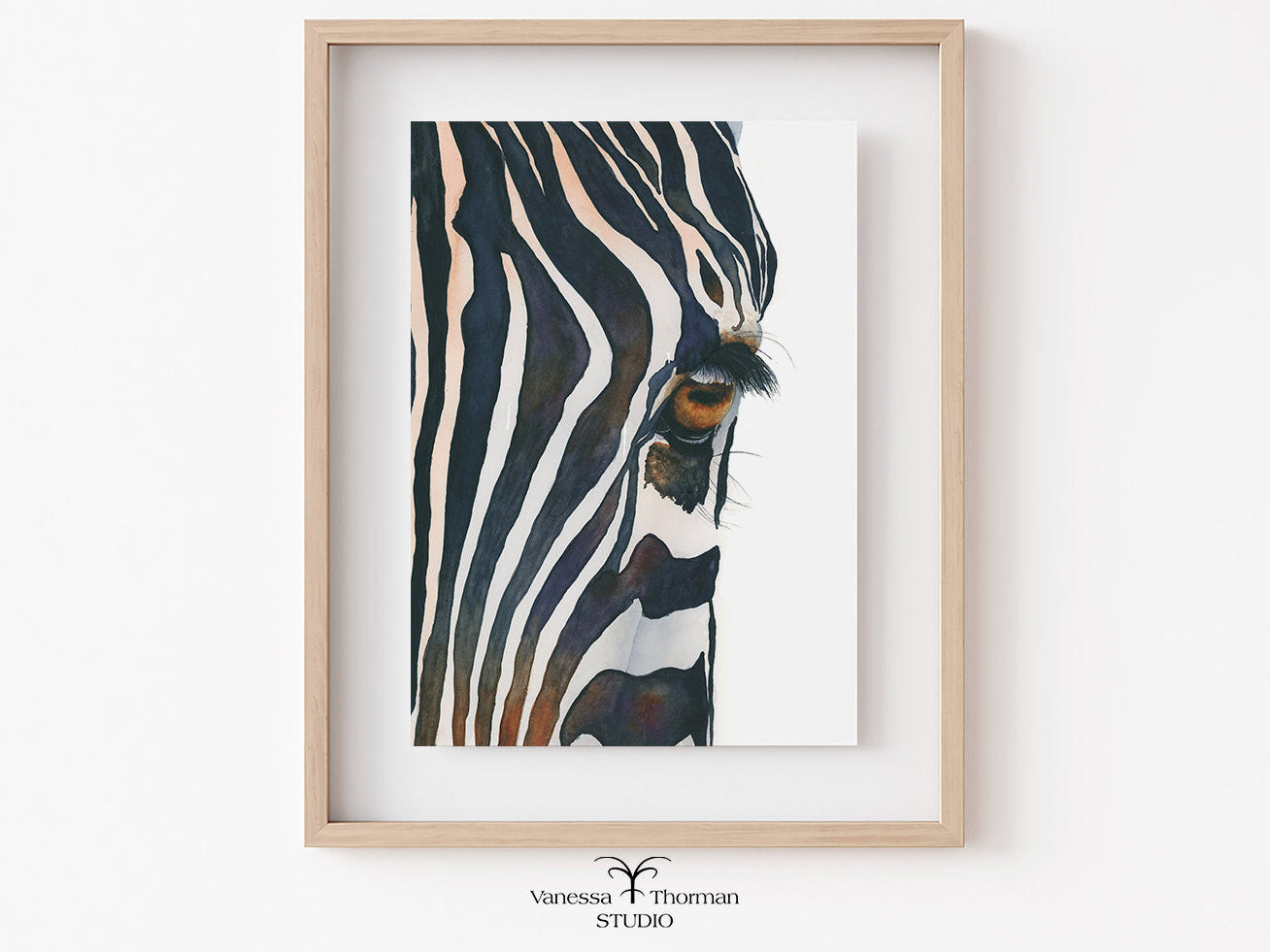 Framed artwork of a zebra's eye on a white wall.