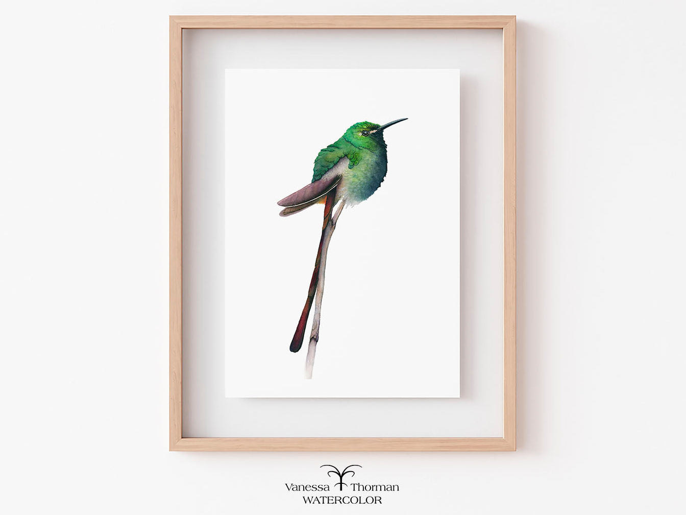 Framed watercolor painting of a green hummingbird on a white background